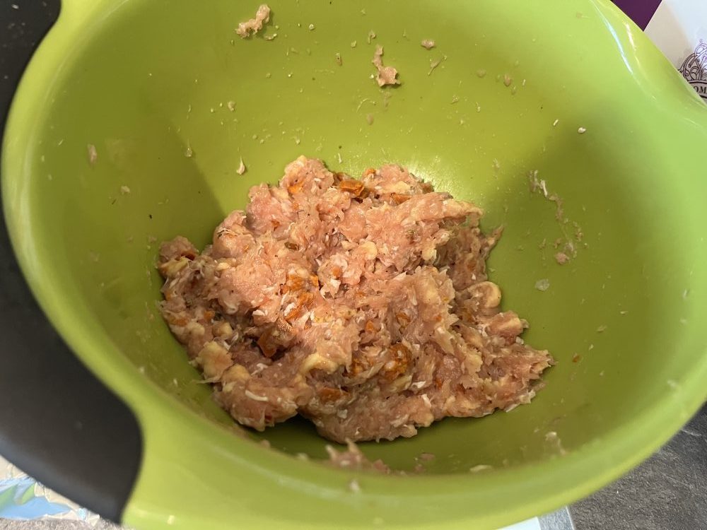 Raw meatball mix in a green bowl.