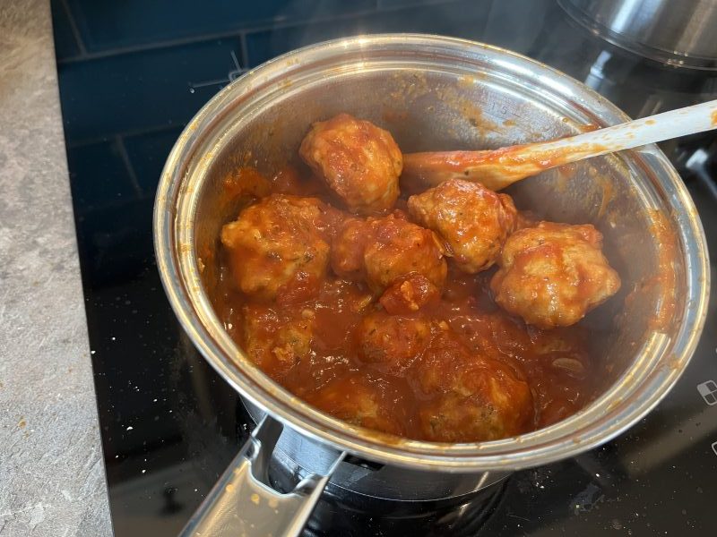 About a dozen meatballs and a tomato sauce in a pan.